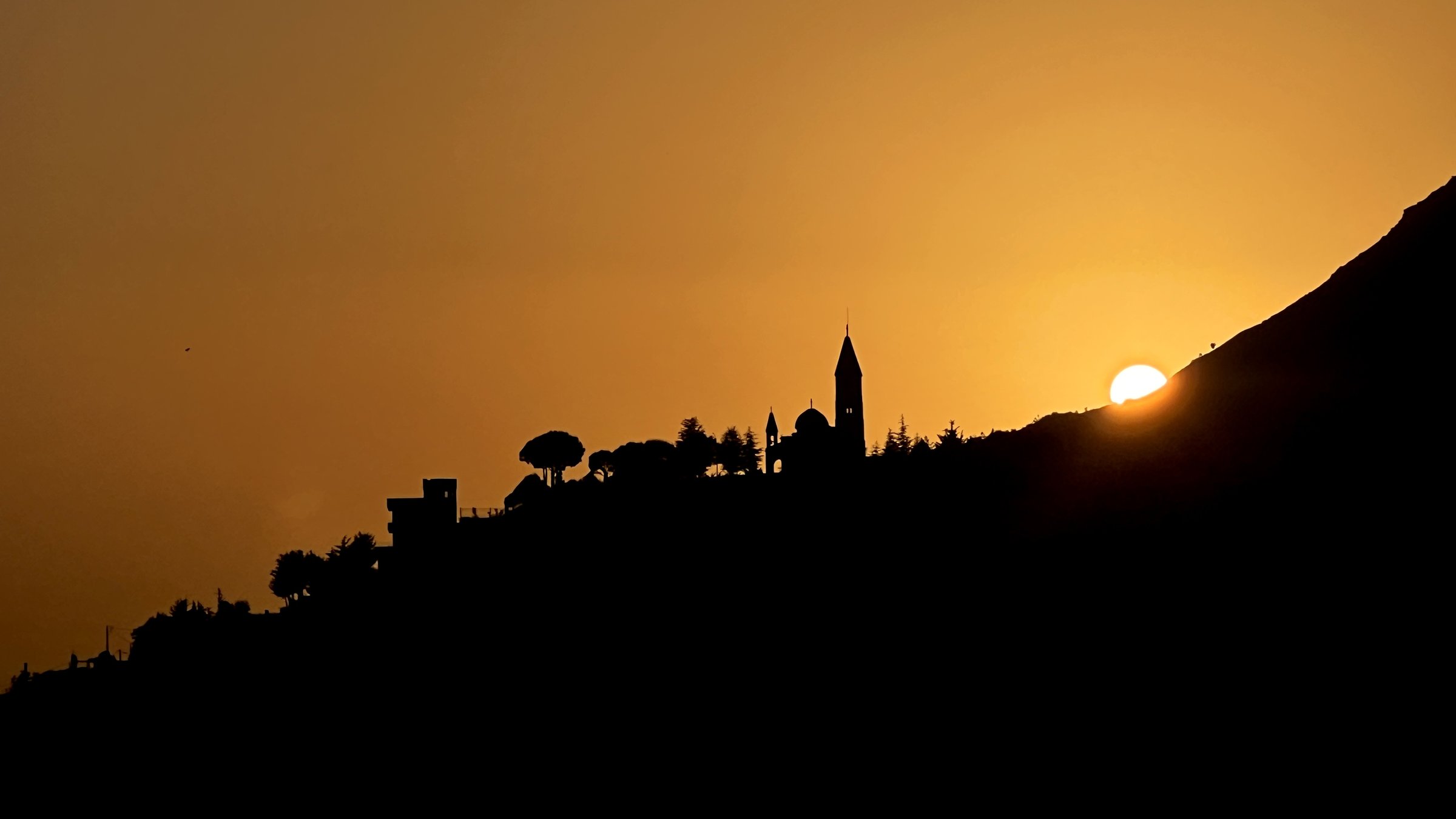 Beirut hillside silhouette at sunset — church and minaret on the ridge