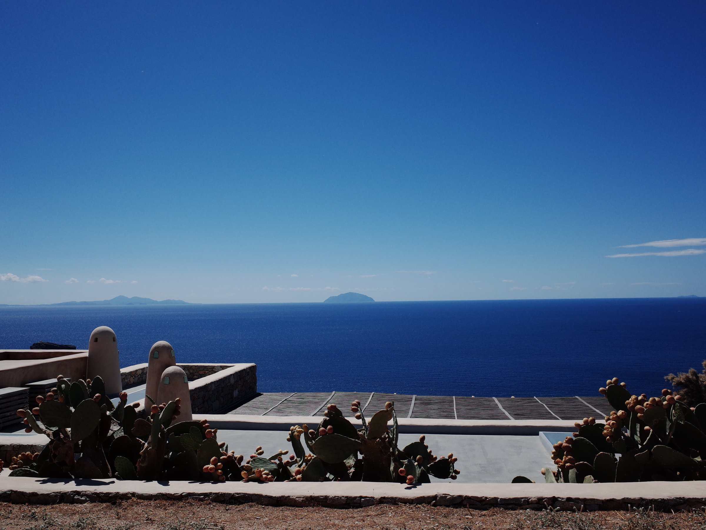 Deep blue Mediterranean view framed by prickly pear cactus
