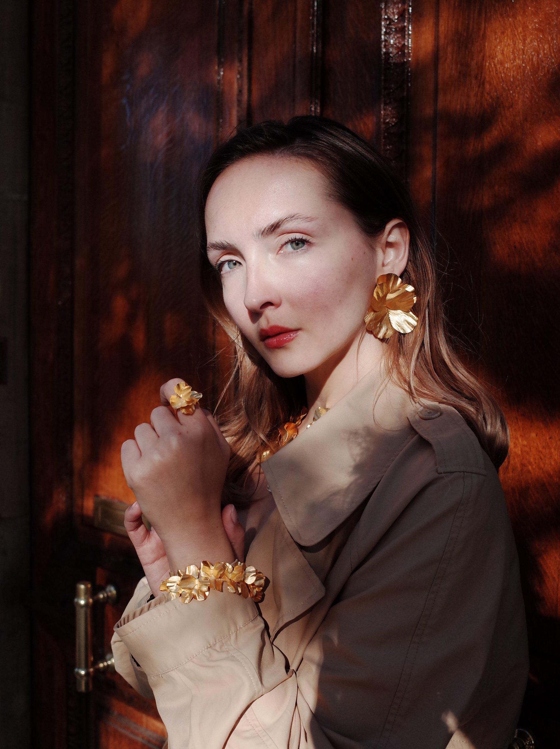 Editorial portrait — gold floral earring, trench coat