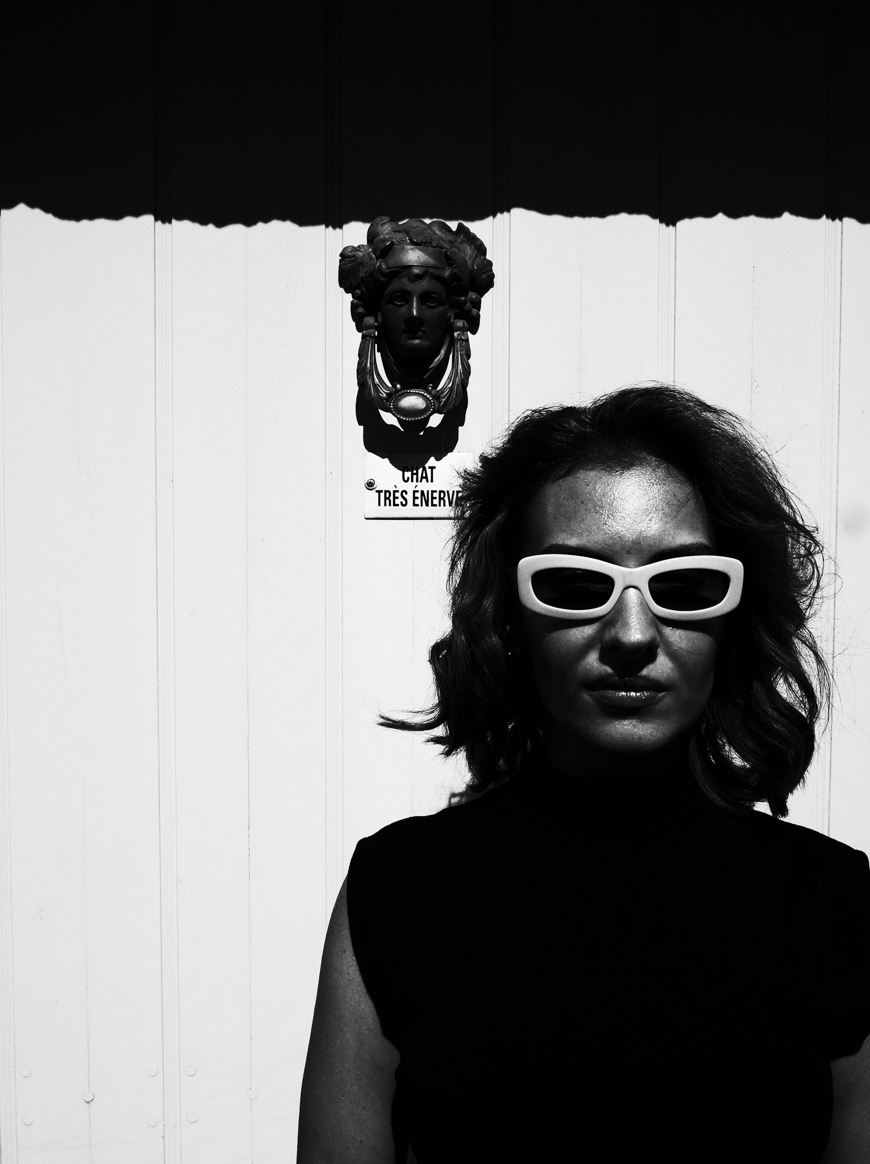 Black and white street portrait — white cat-eye sunglasses